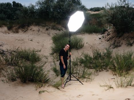 A man with a bright spotlight stands on the sand on an island on the beaches. High quality photo