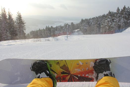 Snowboarder sitting on snow, legs snowboard and slope