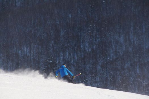 Male skier skiing downhill in mountains snowy day