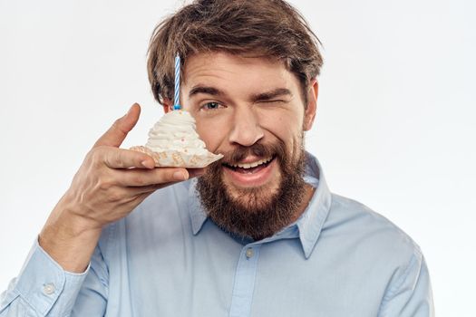 A man with a cake plate and in a blue shirt on a light background birthday party corporate cap. High quality photo