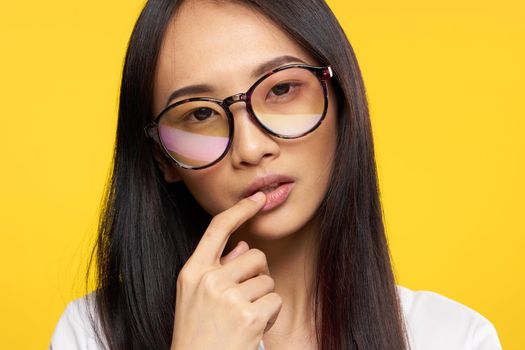 woman asian appearance elegant style glasses hand near face yellow background. High quality photo