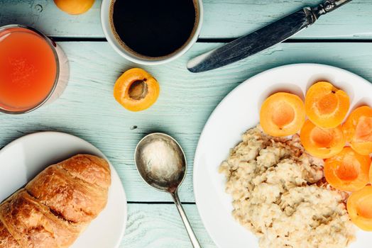 Breakfast set. Porridge with sliced apricot, cup of coffee, glass of grapefruit juice and croissant