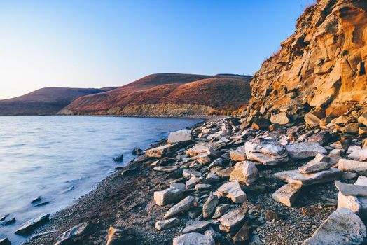 Hilly lake shore in sunrise light. Autumn morning with clear sky