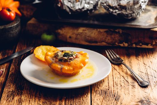 Stuffed pattypan squash on white plate over rustic table