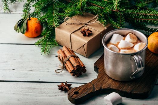 Rustic mug of hot chocolate with marshmallows on cutting board