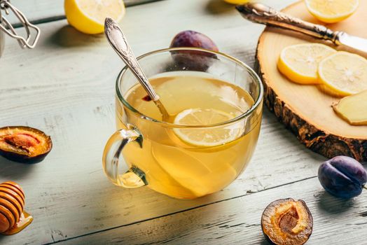 Cup of tea with lemon, honey and ginger over wooden surface