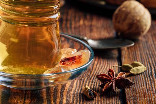 Arabic tea with star anise, cardamom and dried lime in oriental glass over wooden surface