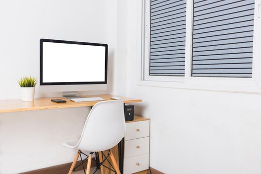 Computer monitor with white blank screen on the business desk with wireless mouse, keyboard at home office over white wall background, Photo of equipment contemporary workspace