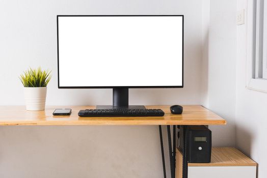 Computer monitor with white blank screen on the business desk with wireless mouse, keyboard at home office over white wall background, Photo of equipment contemporary workspace