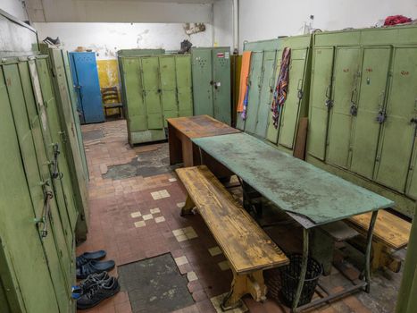 old dirty locker room in soviet factory with table and benches