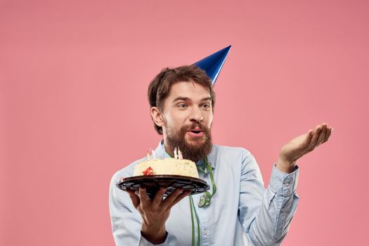 Bearded man with cake tongue on a pink background cropped view and a blue cap on his head. High quality photo