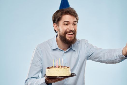 cake in a plate and birthday man with a cap on his head blue backgroun. High quality photo