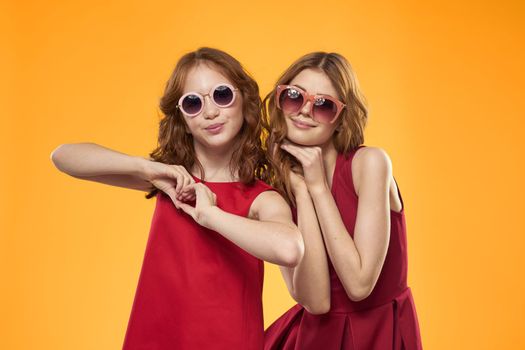 Two sisters and fun sunglasses fashion Friendship yellow background family. High quality photo