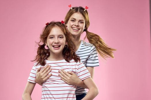 funny girlfriends with clothespins hair on a pink background sisters. High quality photo