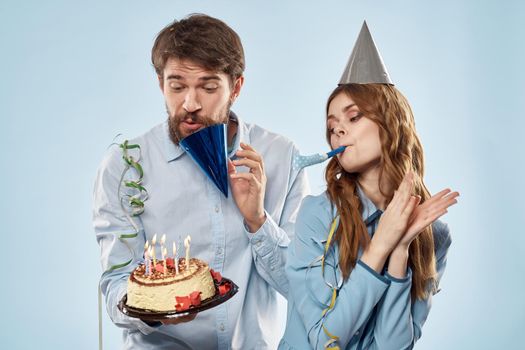 Birthday man woman in party hats on a blue background and cake with candles. High quality photo