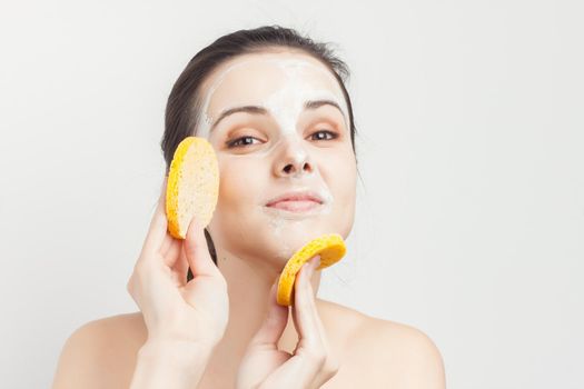 attractive brunette naked shoulders face mask hand sponge skin care. High quality photo