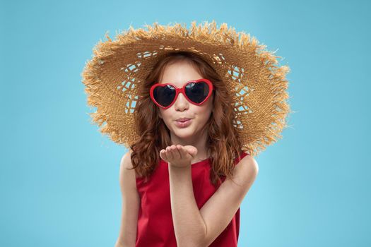 Girl in a beach Straw hat in sunglasses curly hair fun blue background. High quality photo