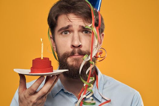 Birthday boy in a cap with a birthday cake in his hand and a candle. High quality photo