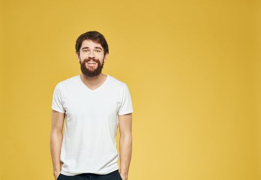 Portrait of a man on a yellow background in a white T-shirt and dark trousers. High quality photo