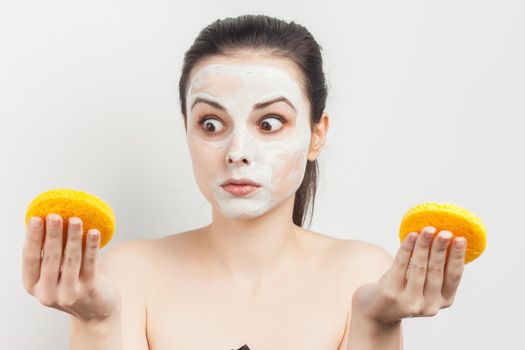 cheerful woman naked shoulders sponges in hands mask on face. High quality photo