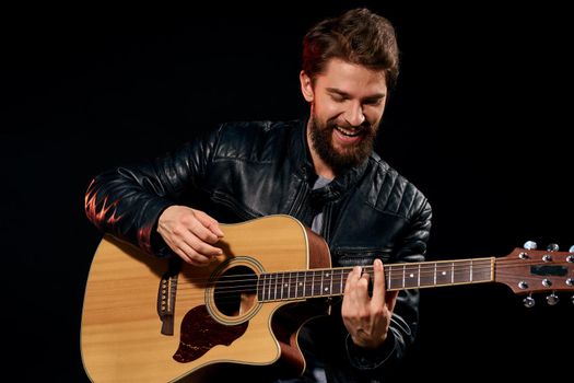 A man with a guitar in his hands leather jacket music performance rock star modern style dark background. High quality photo