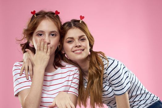 cheerful girl and woman on a pink background sisters family emotions. High quality photo