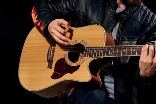 A man with a guitar in his hands leather jacket music performance rock star modern style dark background. High quality photo