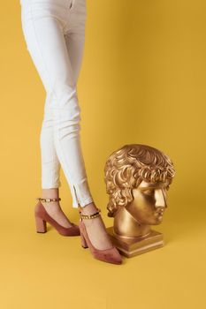 Female feet head sculptures golden color luxury fashion yellow background. High quality photo
