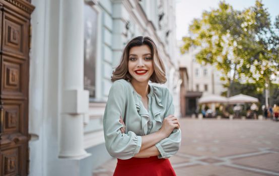 a woman in a red skirt stands near the door of a historic building museum city streets. High quality photo