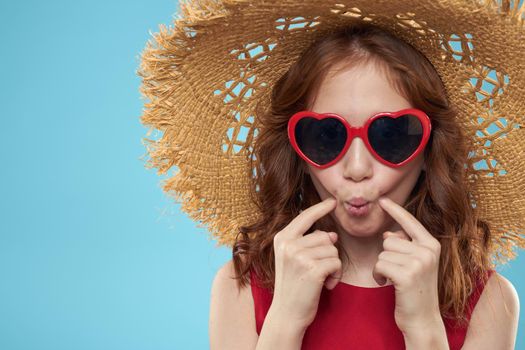 Girl in a beach Straw hat in sunglasses curly hair fun blue background. High quality photo