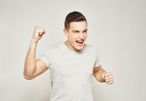 A man in a white t-shirt gestures with his hands emotions studio light background. High quality photo