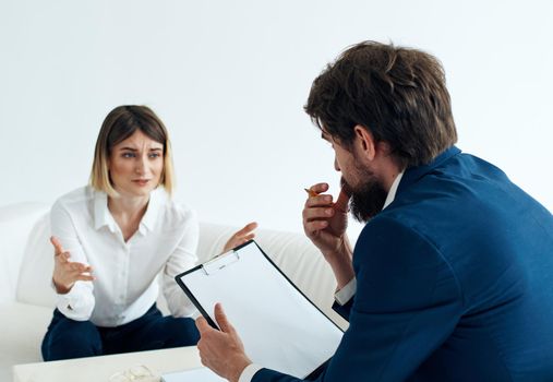 a man with documents sits on the sofa and women opposite at the table. High quality photo