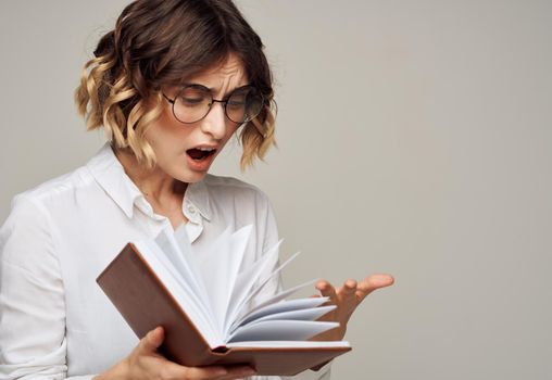 Emotional woman gestures with her hands on a gray background glasses on her face for hairstyle education. High quality photo