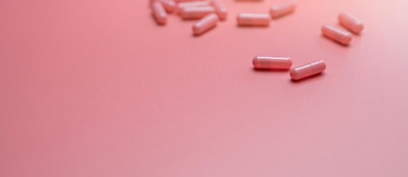 Pink capsules pill spread on pink background. Vitamins and supplements for healthy skin, collagen boost, and acne treatment concept. Online pharmacy. Pharmacy store banner. Pharmaceutical industry.