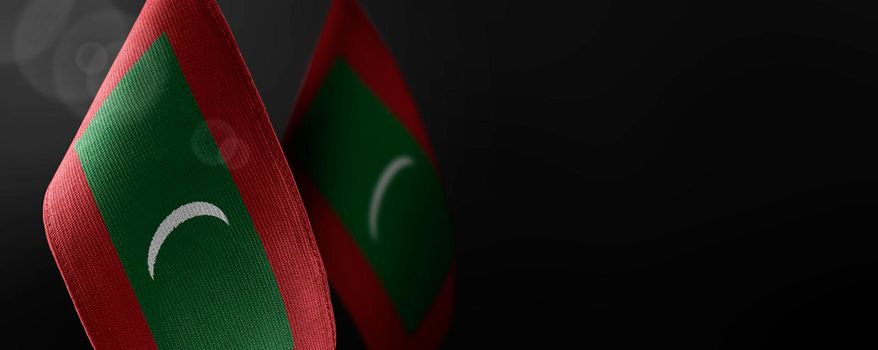 Small national flags of the Maldives on a dark background.