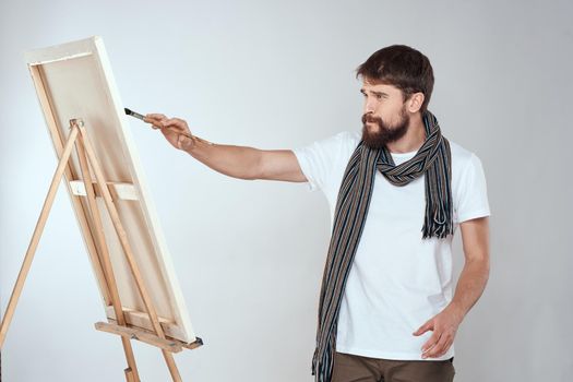 male artist painting on easel art lifestyle light background. High quality photo