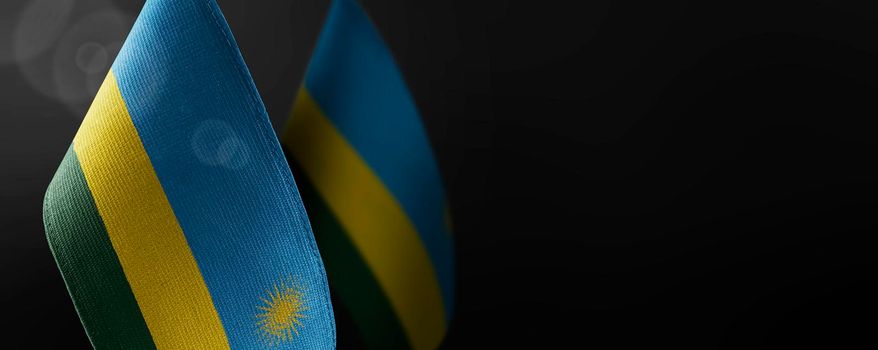 Small national flags of the Rwanda on a dark background.