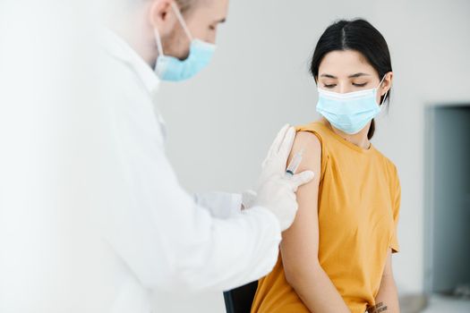 professional doctor holds his hand on the shoulder of a woman in a yellow t-shirt and a medical mask. High quality photo
