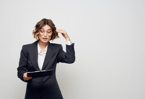 A woman with documents in a folder on a light background gestures with her hands. High quality photo