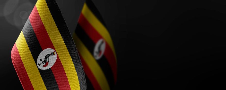 Small national flags of the Uganda on a dark background.