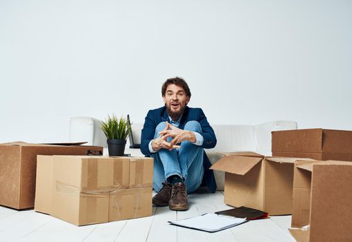 Business man sitting on the floor with boxes unpacking documents to the office manager. High quality photo