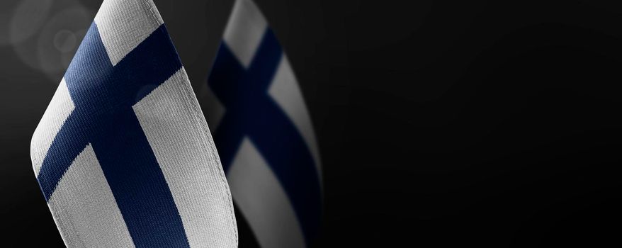 Small national flags of the Finland on a dark background.