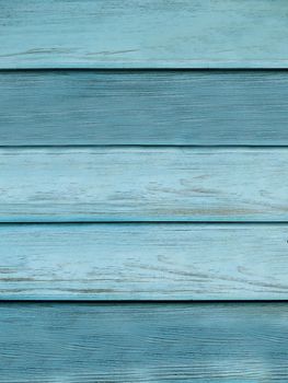 The wall is made of planks with a textured surface of light blue color.Texture or background