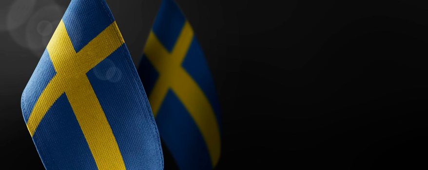 Small national flags of the Sweden on a dark background.