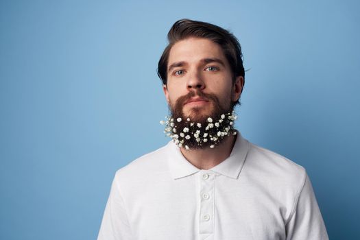 Man in white t-shirt beard flowers decoration blue background. High quality photo