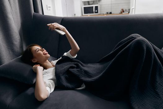 woman with a mobile phone in front of her eyes lies on the sofa top view. High quality photo