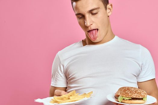 man in white t-shirt hamburger lifestyle pink background eating. High quality photo