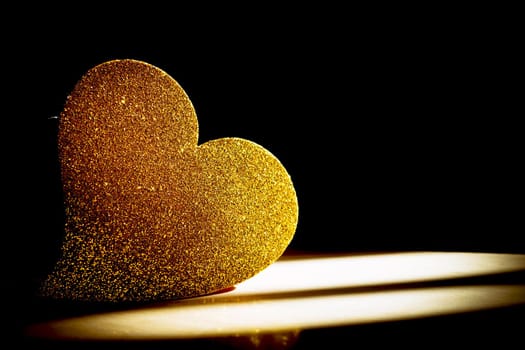 Golden shiny heart on black background