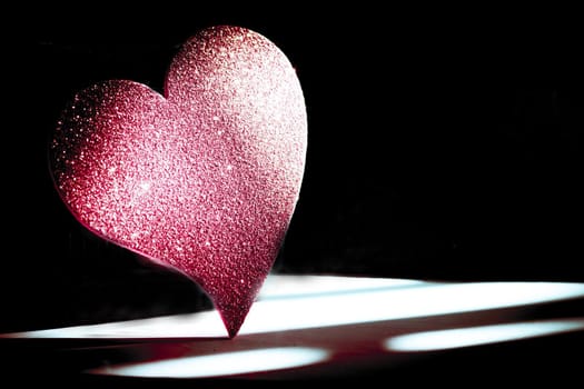 Golden shiny heart on black background