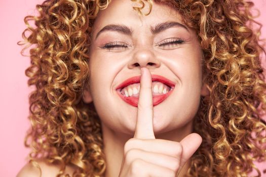 woman curly hair Close-up face closed eyes smile finger near mouth cropped view